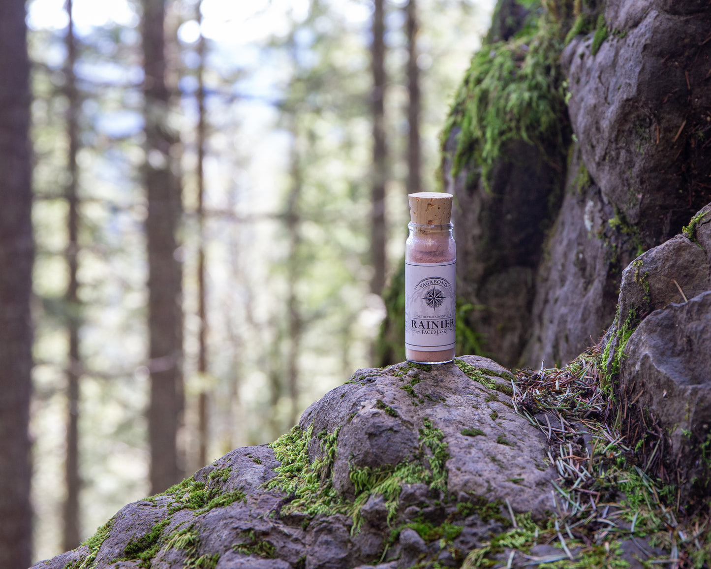 Rainier natural clay mask in corked glass bottles displayed against a mountainside backdrop.
