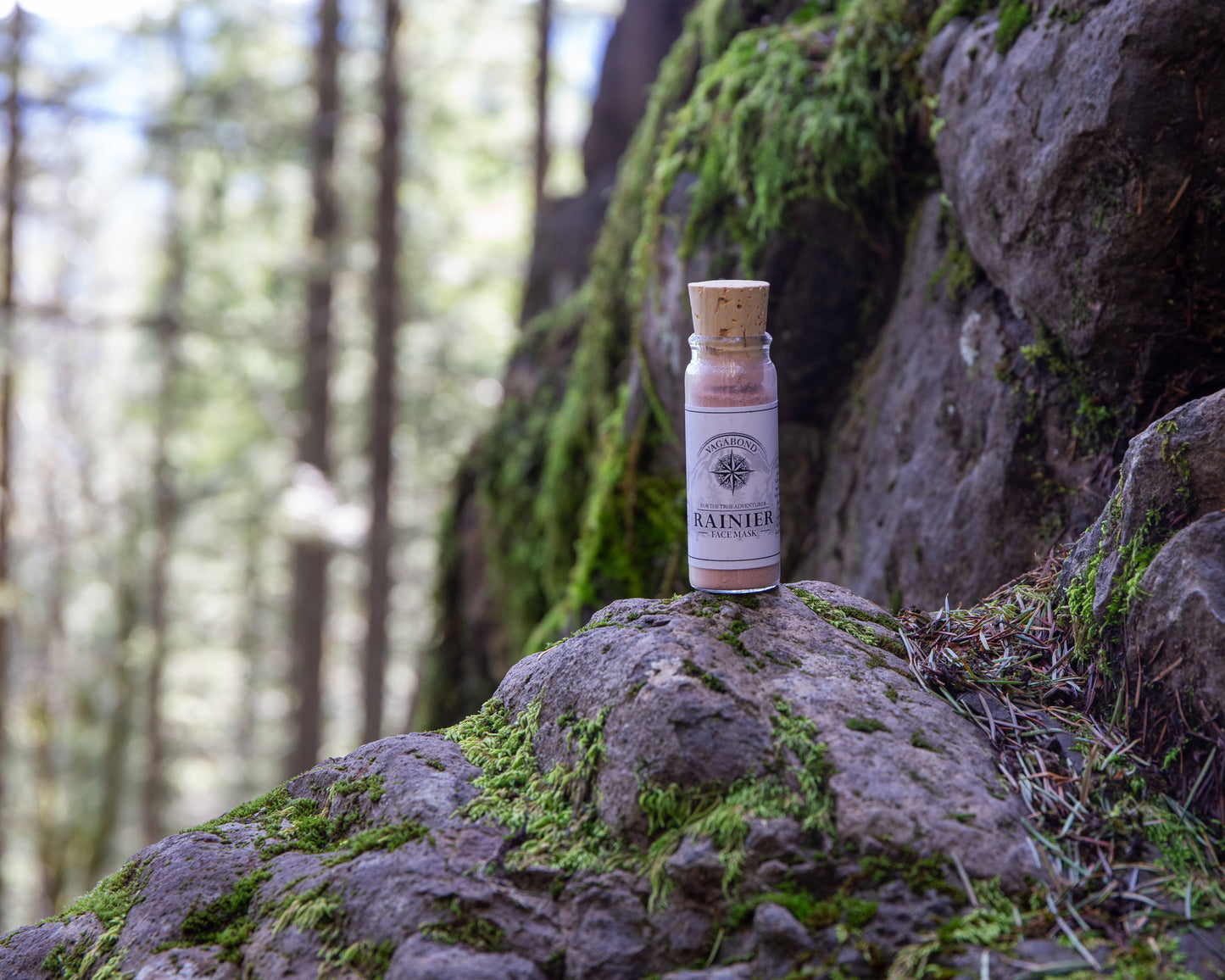 Rainier natural clay mask in corked glass bottles displayed against a mountainside backdrop.