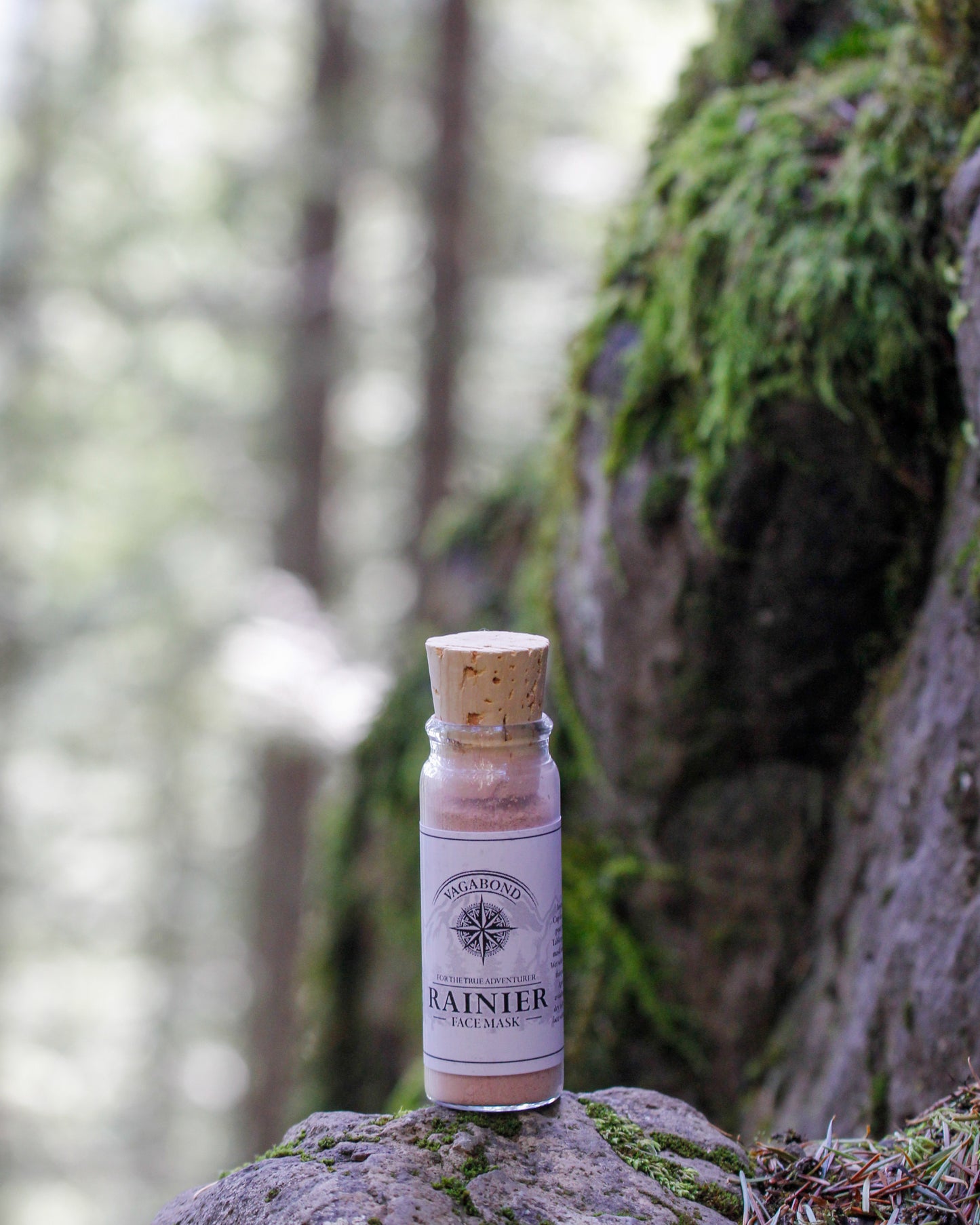 Rainier natural clay mask in corked glass bottles displayed against a mountainside backdrop.