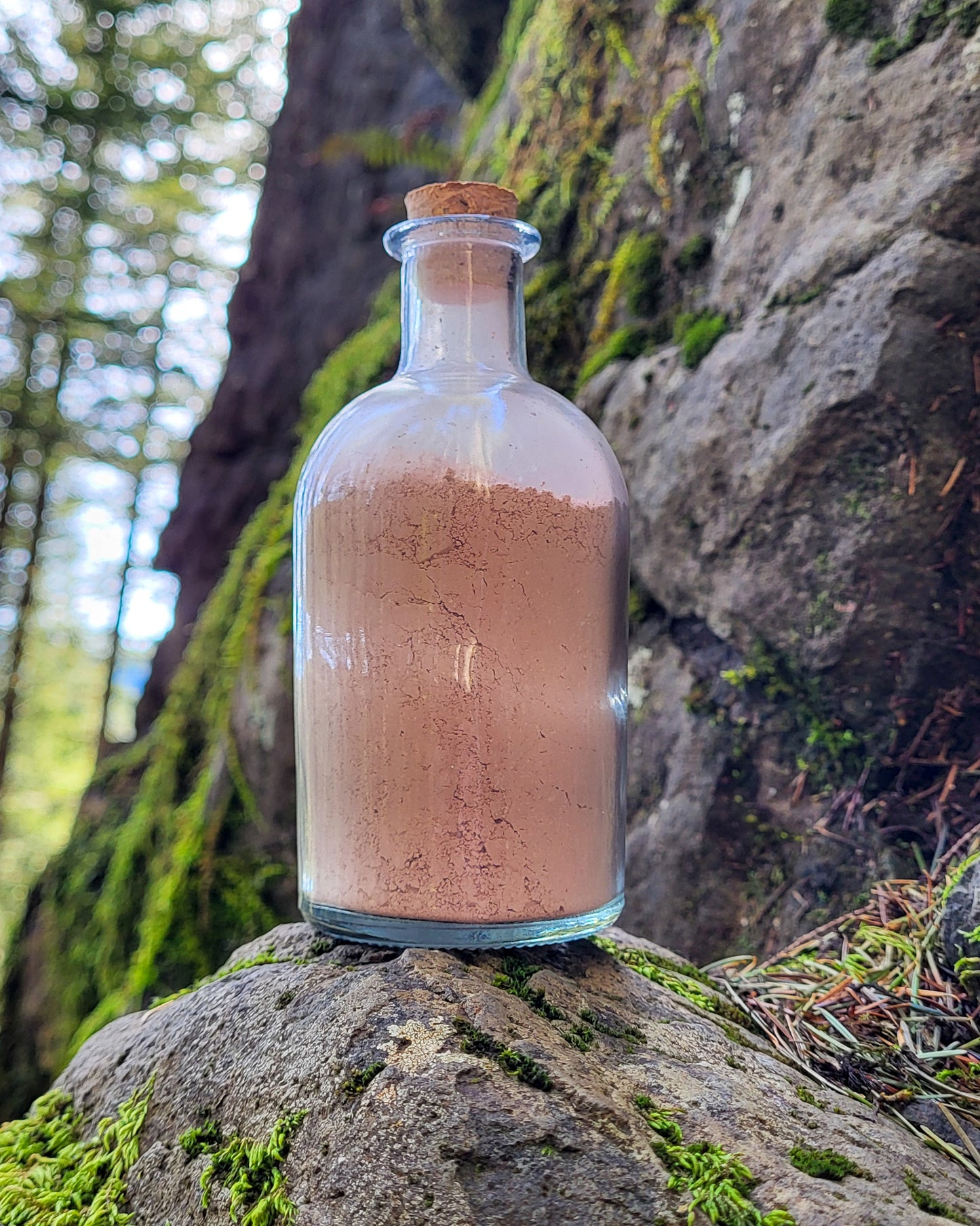 Rainier natural clay mask in corked glass bottles displayed against a mountainside backdrop.