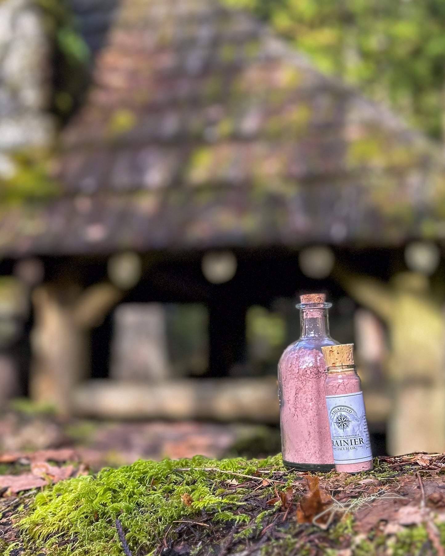Rainier natural clay mask in corked glass bottles displayed against a cabin backdrop.