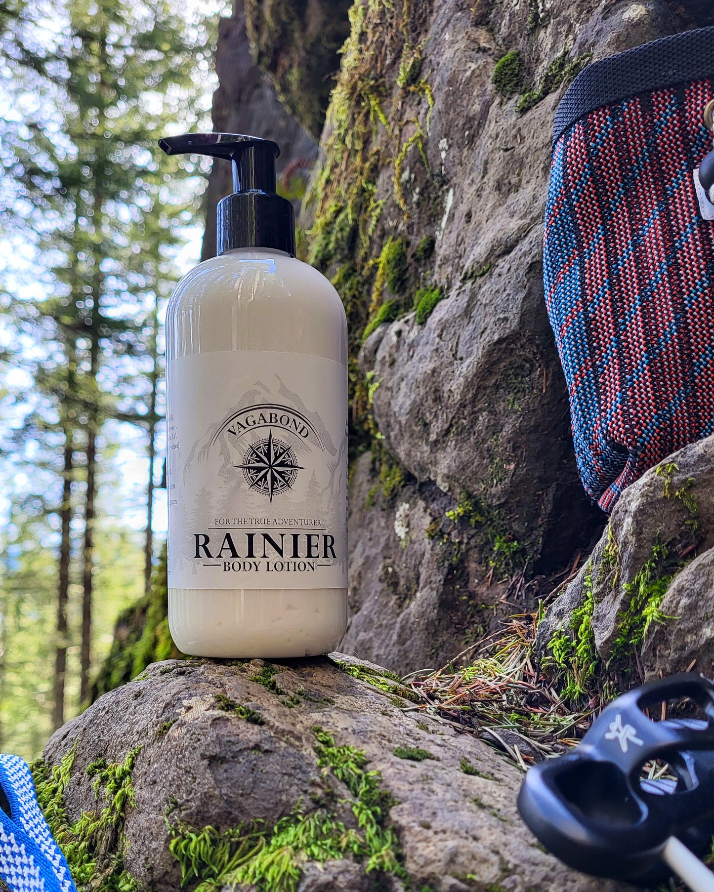 Rainier natural lotion warm cinnamon scent displayed with climbing gear against a mountainside backdrop.
