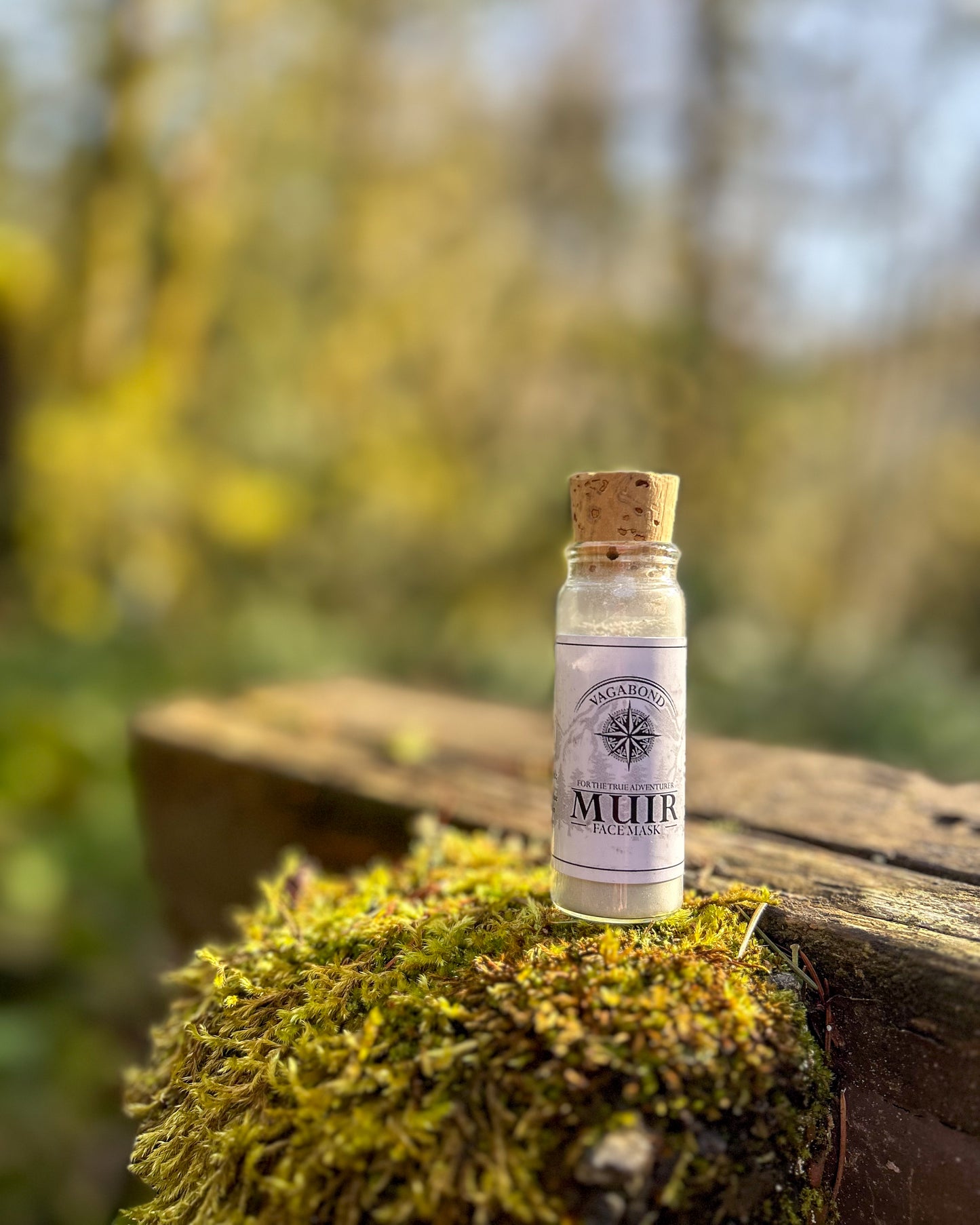 Muir natural clay mask in corked glass bottles displayed on a mossy post backdrop.