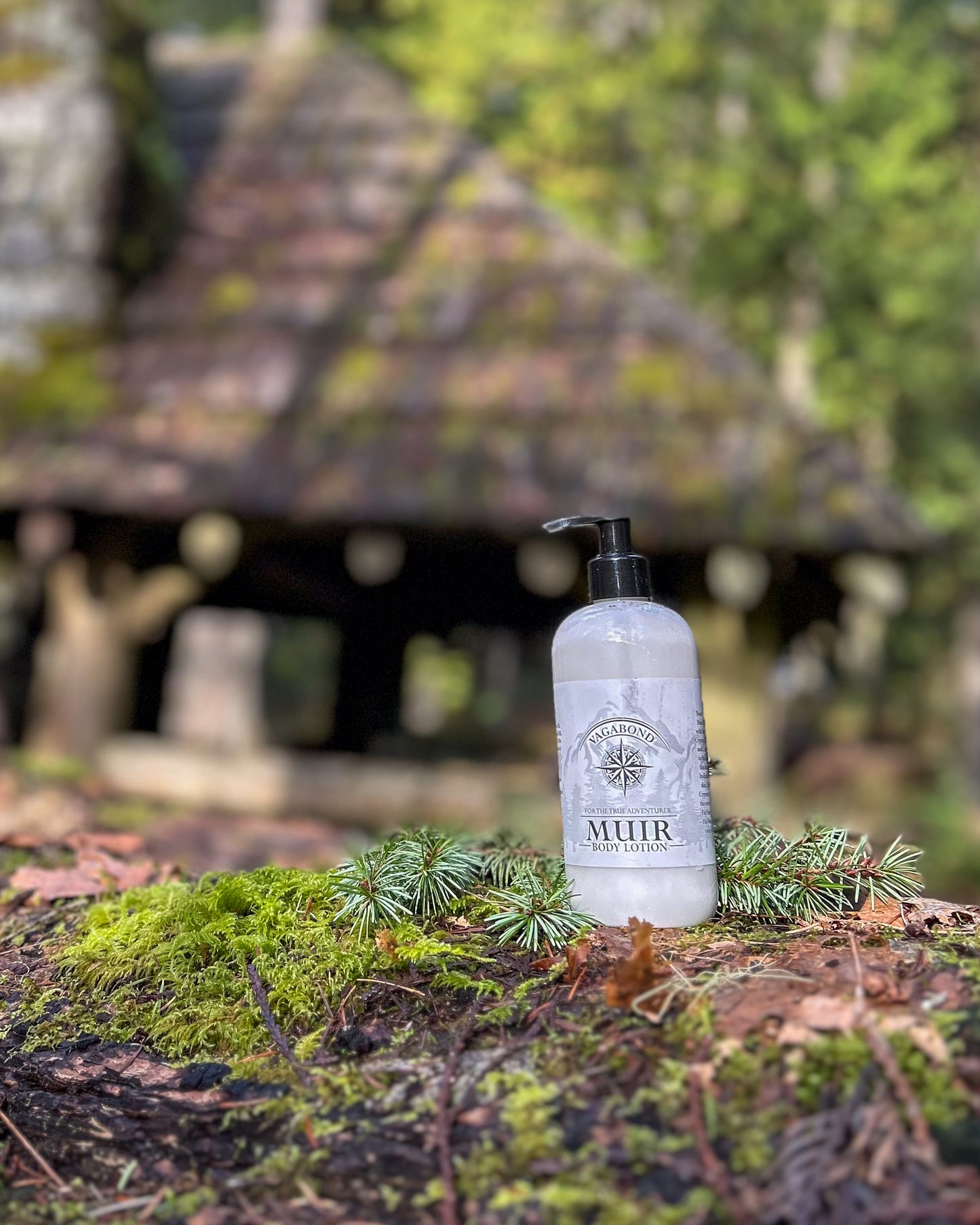 Muir natural lotion evergreen scent displayed with a blurry cabin backdrop