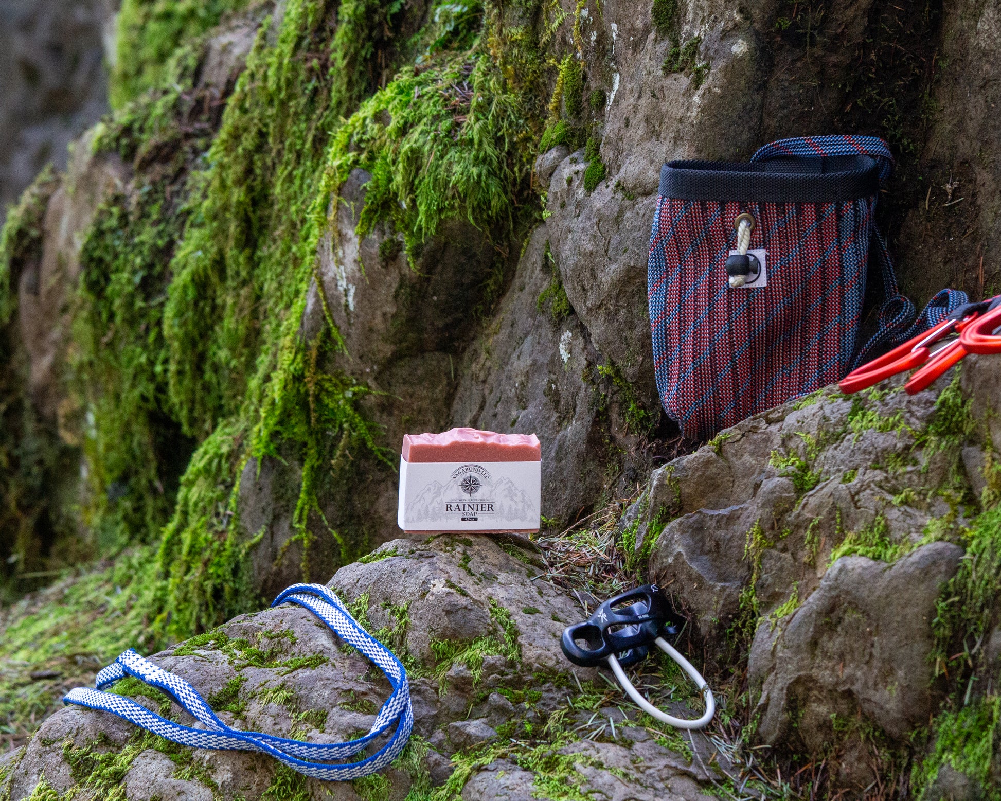 Rainier natural bar soap warm cinnamon scent on a log displayed with climbing gear against a mountainside backdrop.