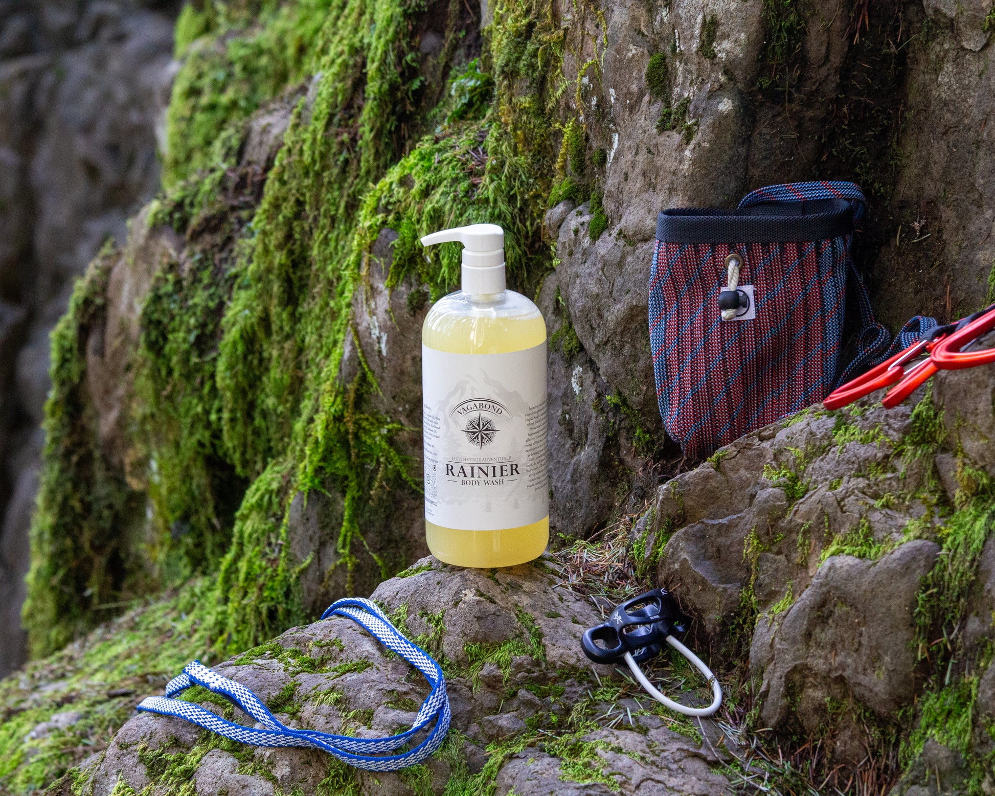 Rainier natural body wash warm cinnamon scent displayed with climbing gear against a mountainside backdrop