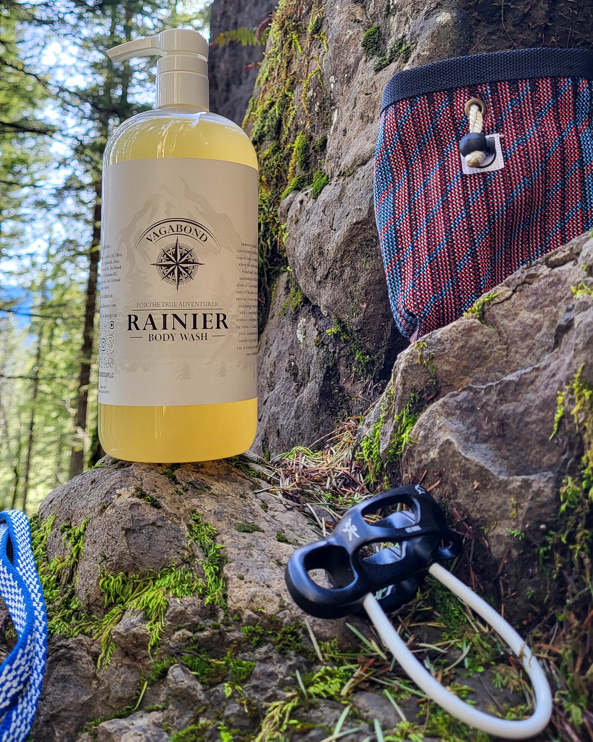 Rainier natural body wash warm cinnamon scent displayed with climbing gear against a mountainside backdrop