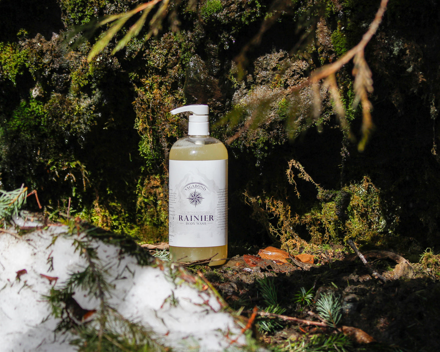 Rainier natural body wash warm cinnamon scent displayed against a wet mossy backdrop