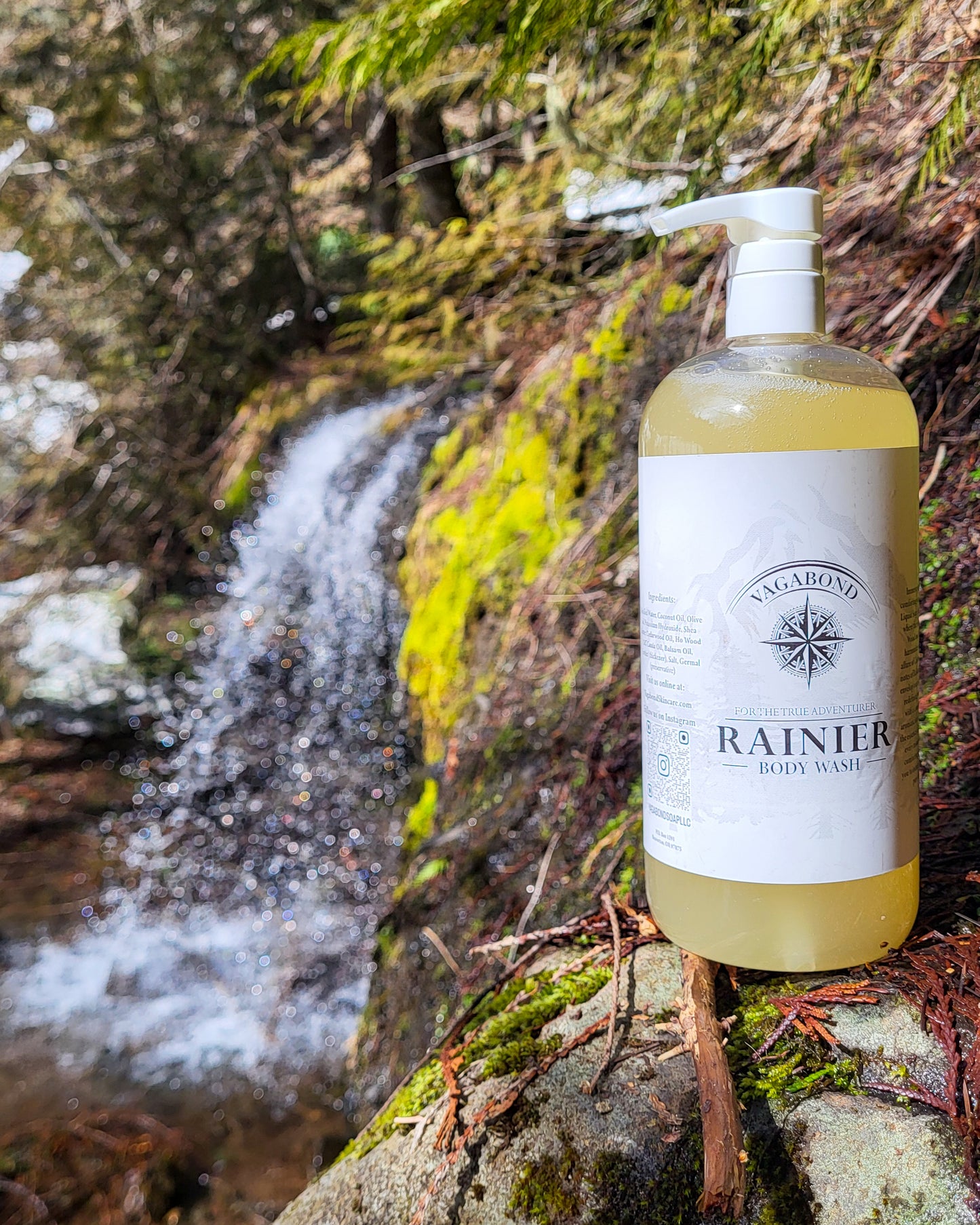 Rainier natural body wash warm cinnamon scent displayed against a mountainside waterfall backdrop