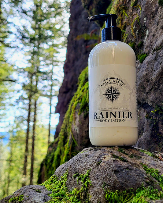 Rainier natural lotion warm cinnamon scent displayed against a mountainside backdrop.