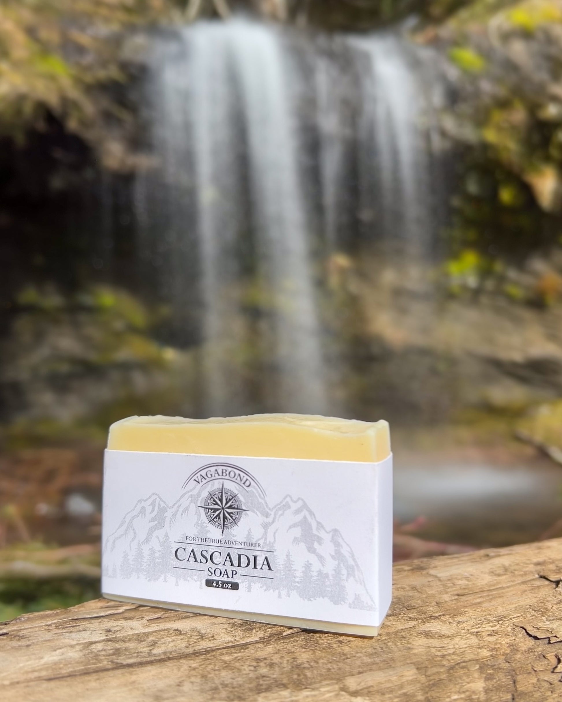 Cascadia natural bar soap lemon citrus scent on a log displayed against a blurry waterfall backdrop.