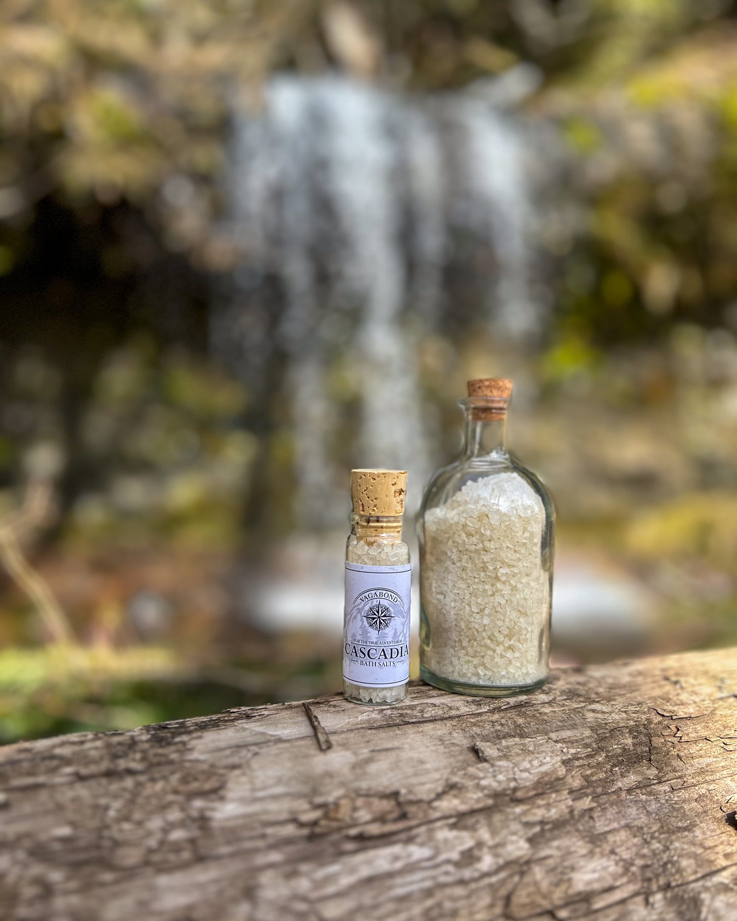 Cascadia natural bath salts lemon citrus scent in corked glass bottle displayed against a blurry waterfall backdrop