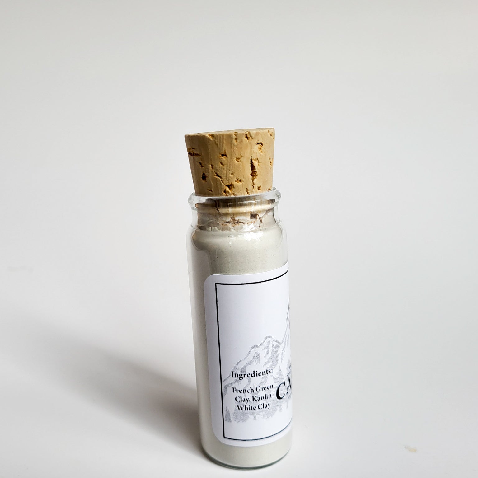 Cascadia natural clay mask in corked glass bottle displayed against a plain white backdrop showing ingredients on the label