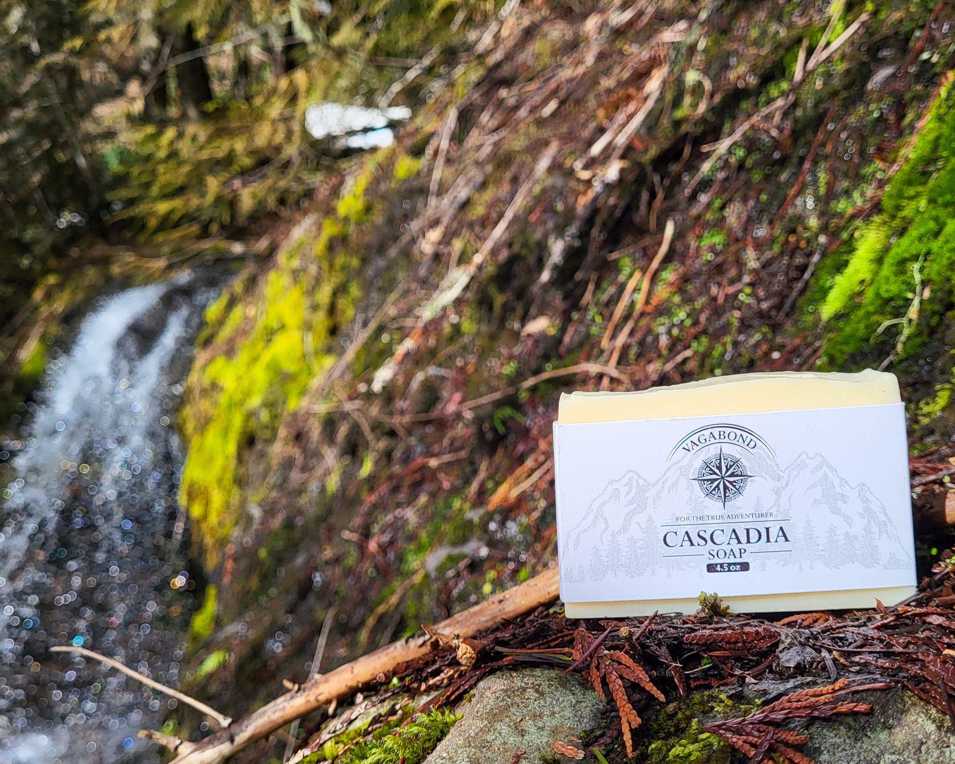 Cascadia natural bar soap lemon citrus scent on a mountainside displayed against a blurry waterfall backdrop.