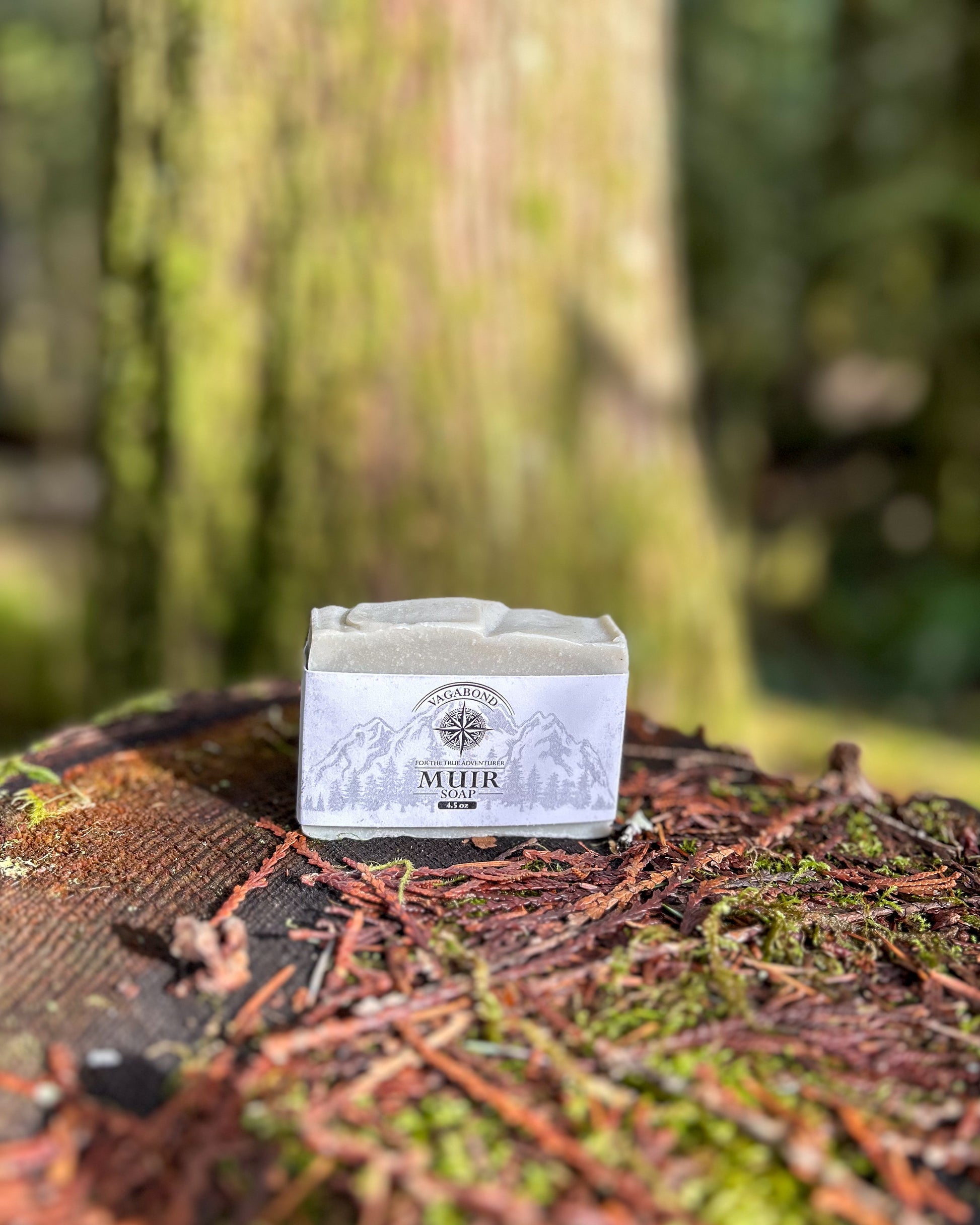 Muir natural bar soap evergreen scent displayed on a mossy stump backdrop