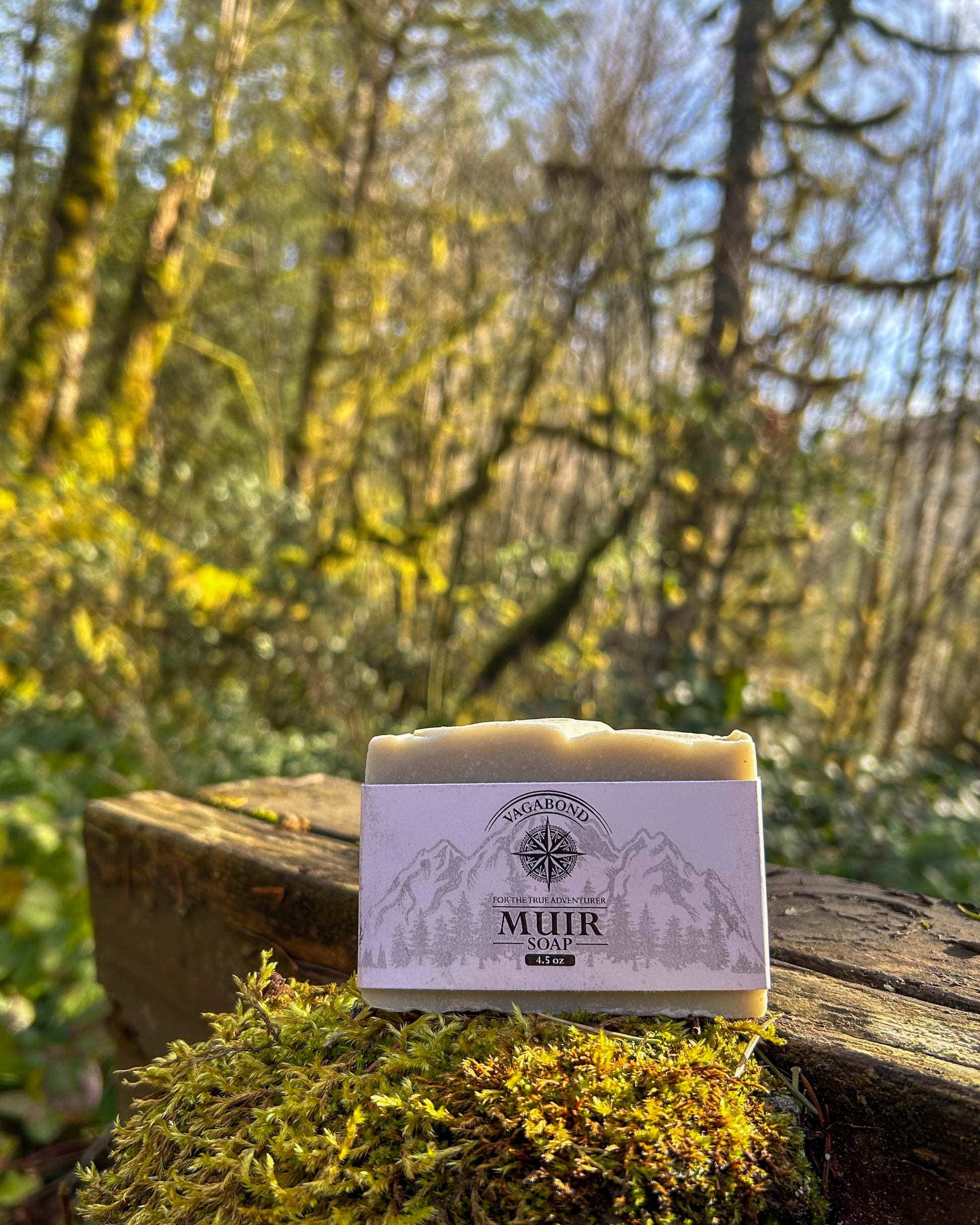 Muir natural bar soap evergreen scent displayed on a mossy post backdrop