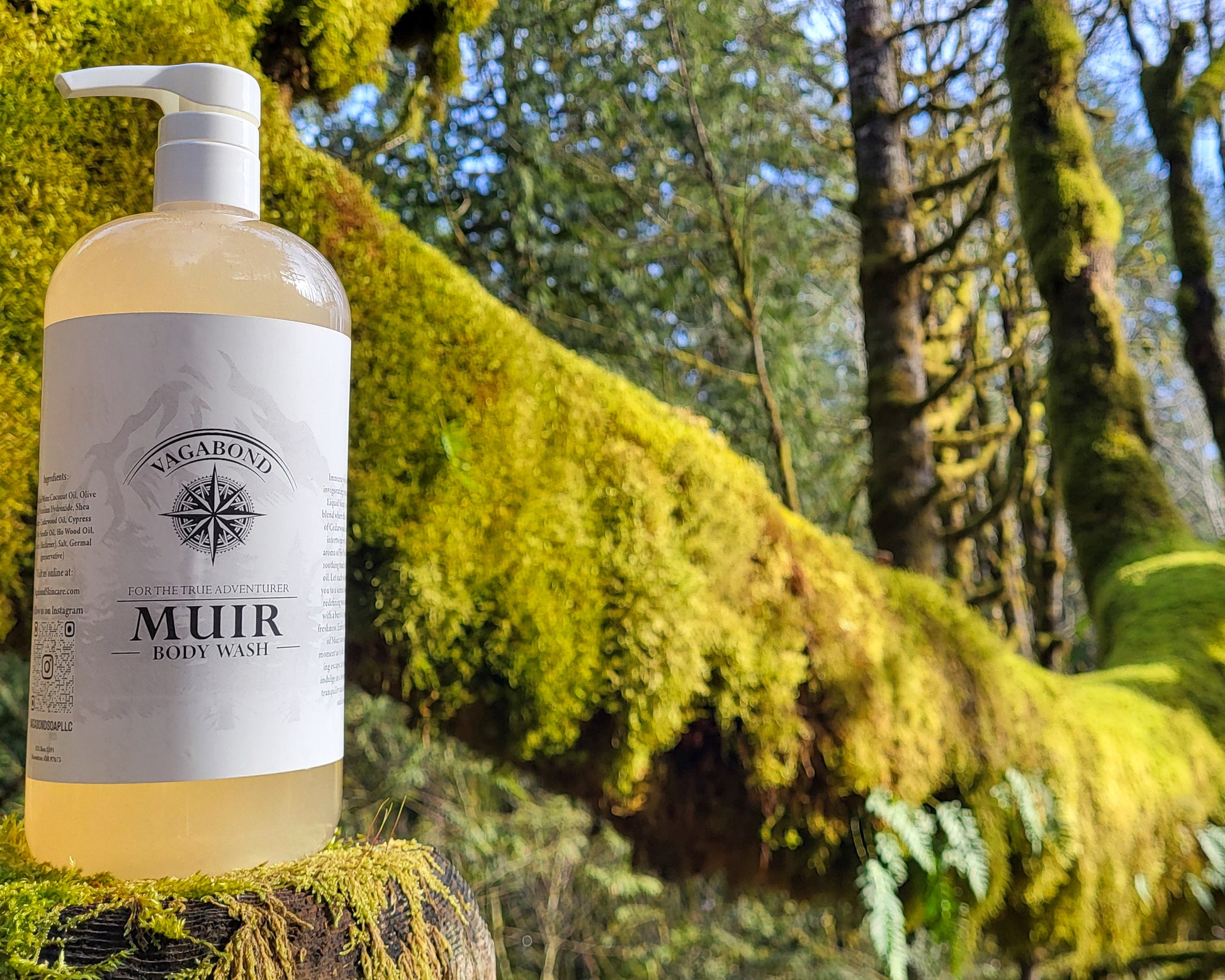 Muir natural body wash evergreen scent in corked glass bottles displayed on a mossy stump with forest backdrop