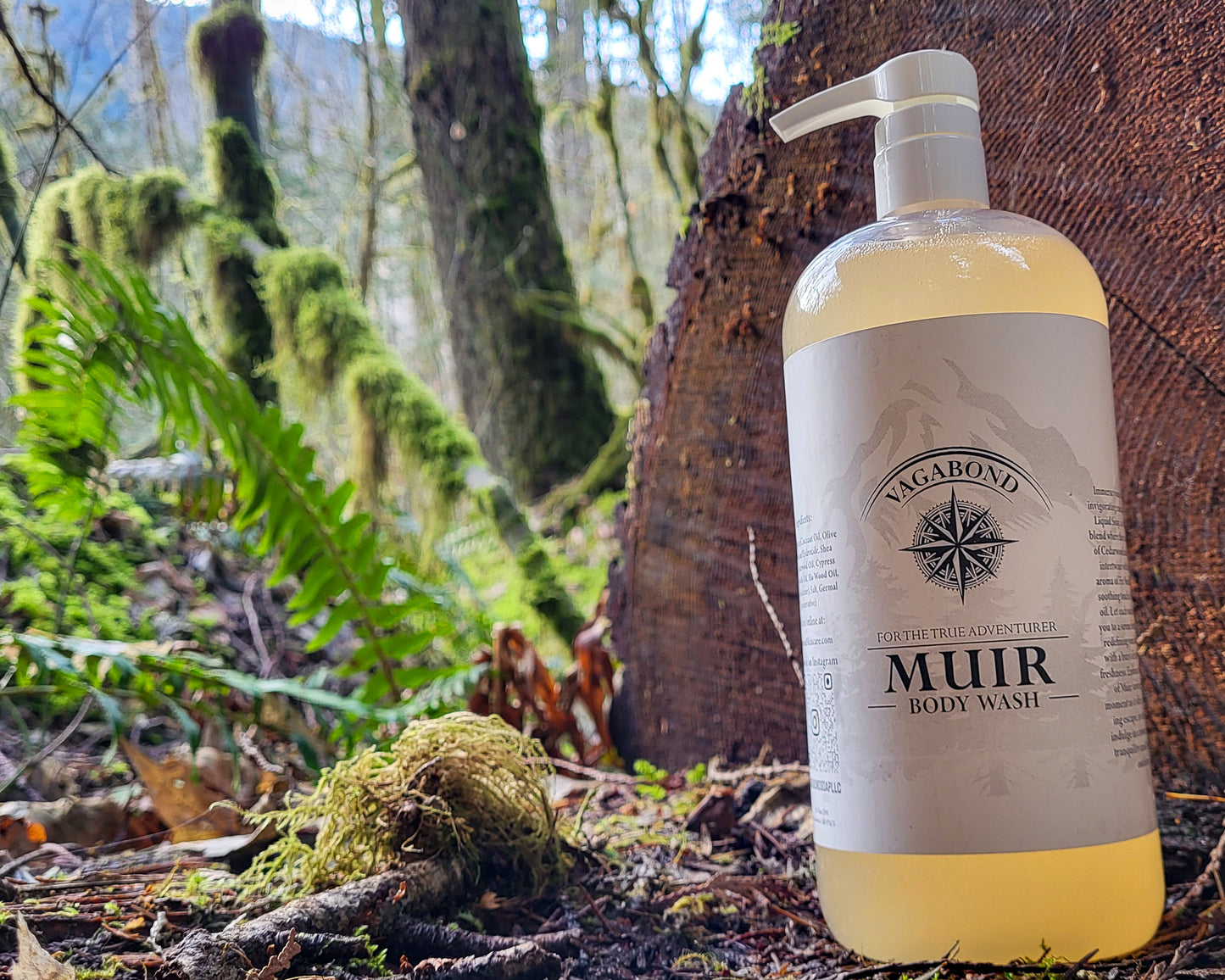 Muir natural body wash evergreen scent in corked glass bottles displayed on a split log with forest and woods backdrop