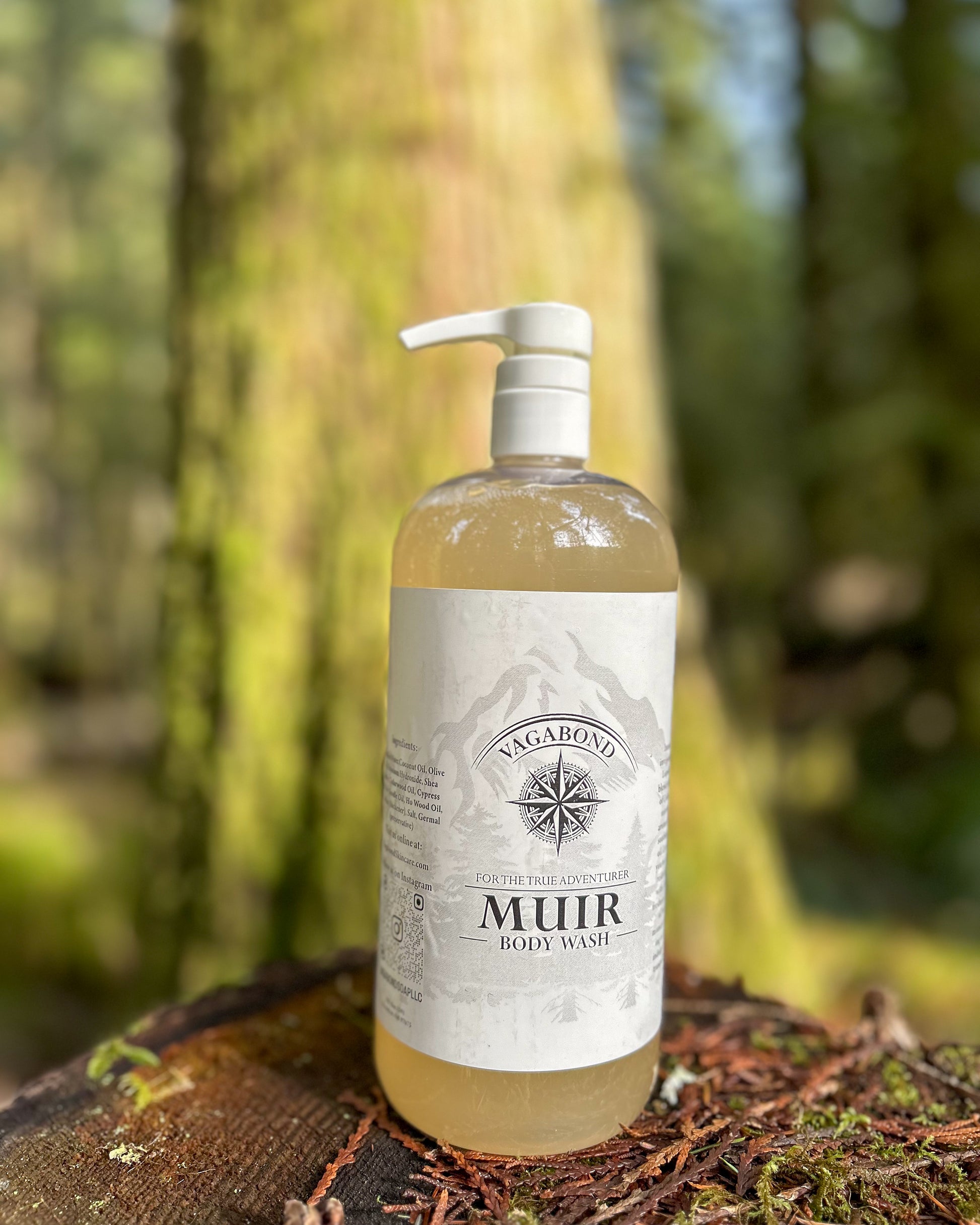 Muir natural body wash evergreen scent in corked glass bottles displayed on a stump with forest backdrop