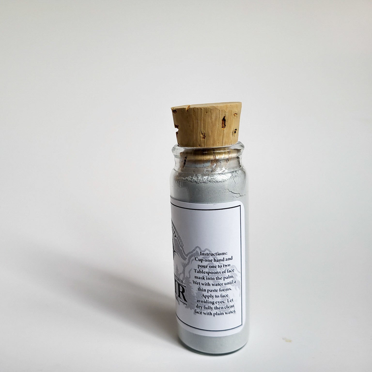 Muir natural clay mask in corked glass bottle displayed against a plain white backdrop showing instructions on the label