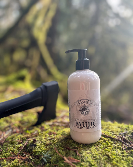 Muir natural lotion evergreen scent displayed on a mossy log with an axe backdrop