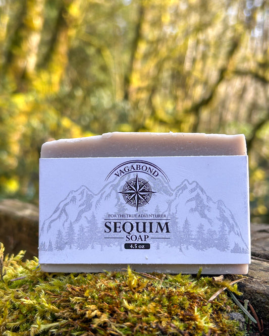 Sequim natural bar soap lavender mint scent on a mossy stump displayed against a blurry forest backdrop.